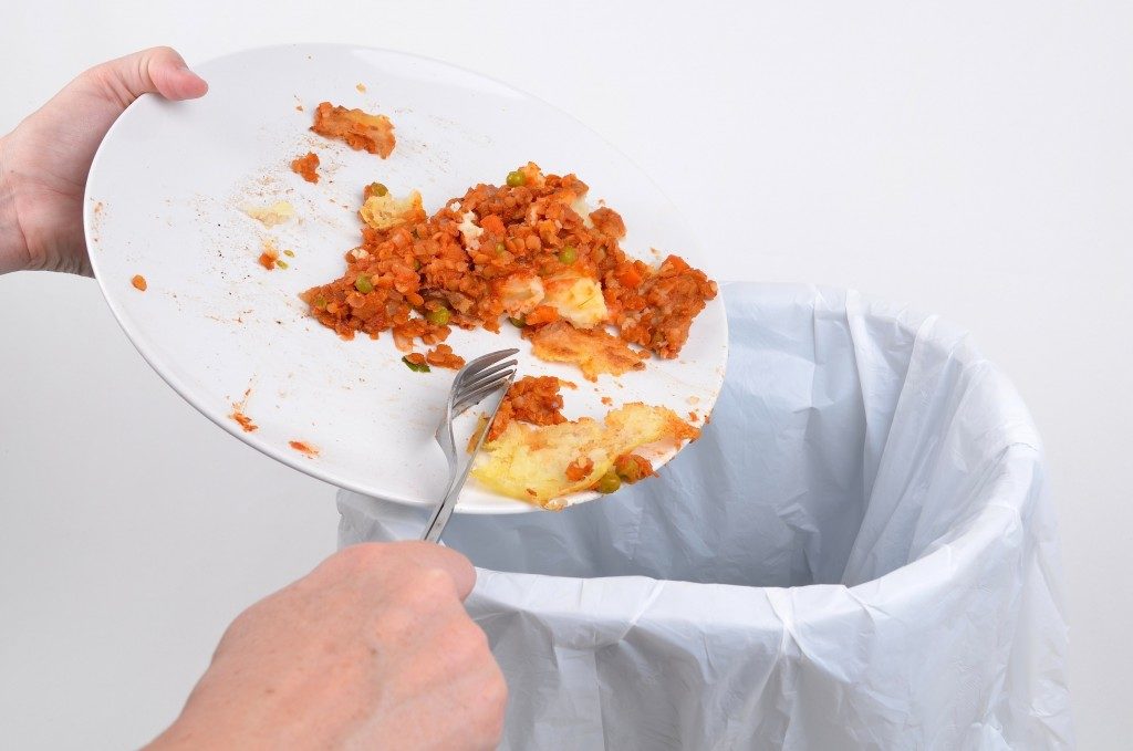 food waste from a plate into a garbage bin