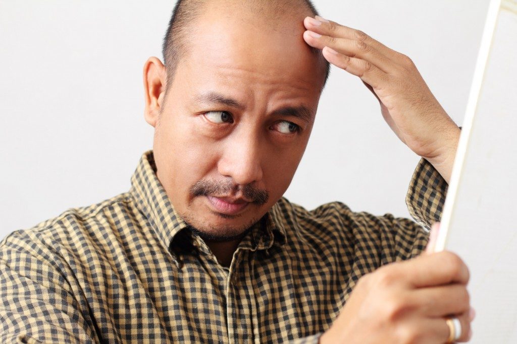 Bald man checking his head