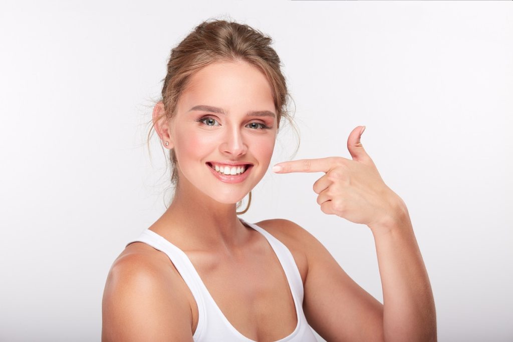 woman pointing at her bright white smile