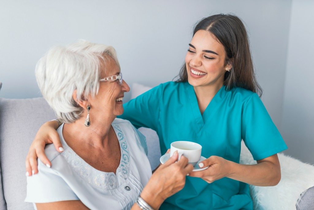 caregiver giving coffee to old woman