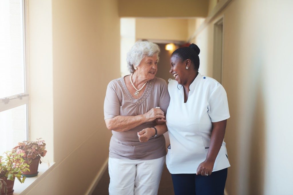 Portrait of happy female caregiver and senior woman walking together at home