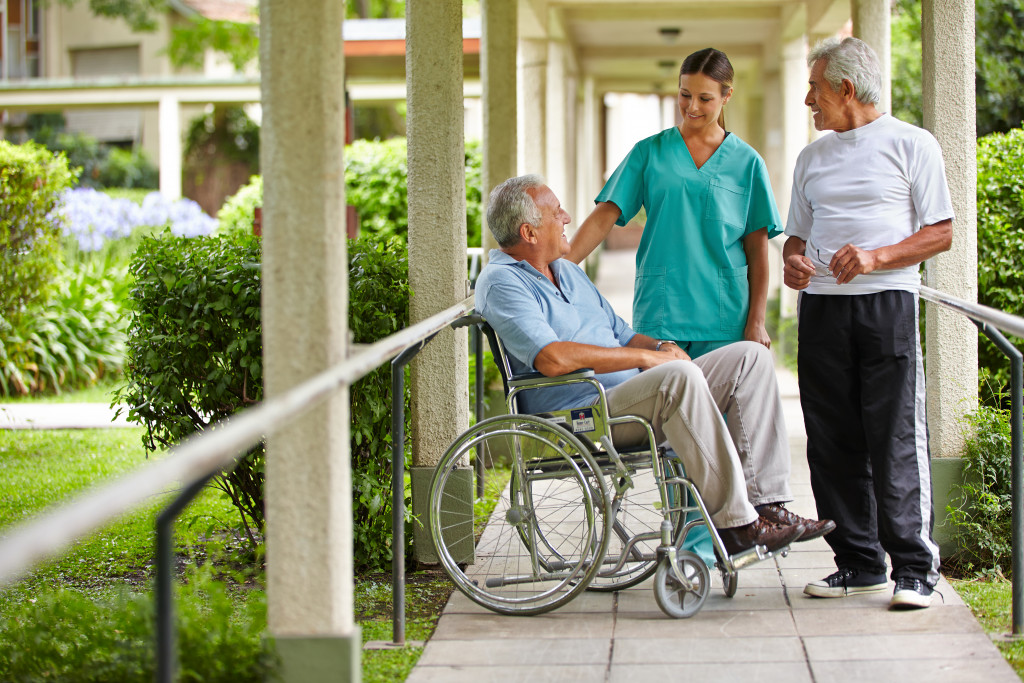 senior in a wheelchair talking to a caregiver on the garden walkway